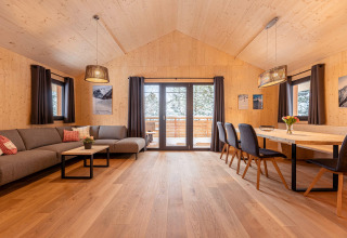 Ruime woonkamer en eetruimte met houtdecor in Nature chalets Turracher Höhe 1, Oostenrijk, met grote ramen.