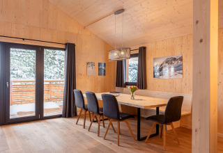 Dining area with wood walls inside Nature chalets Turracher Höhe 1 treehouse with snow view in Austria.