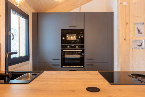 Modern kitchen in Nature Chalets Turracher Höhe 1, Austria, featuring black oven, window, and wood walls.