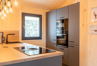 Moderne boomhutkeuken met zwarte kasten in Nature chalets Turracher Höhe 1 in Oostenrijk.