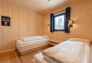 Slaapkamer met twee eenpersoonsbedden, houten wanden en raam bij Nature chalets Turracher Höhe 1, Oostenrijk.
