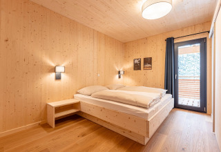 Lichte, moderne slaapkamer met houten wanden en balkon bij Nature chalets Turracher Höhe 1, Oostenrijk.