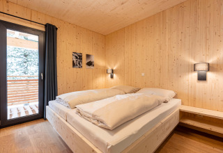 Slaapkamer in een boomhut met houten wanden en balkon bij Nature chalets Turracher Höhe 1 in Oostenrijk.