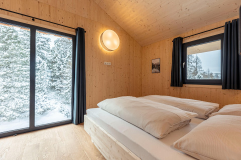 Bedroom in Nature chalets Turracher Höhe 1 tree house, Austria, with wood walls and snowy forest view.