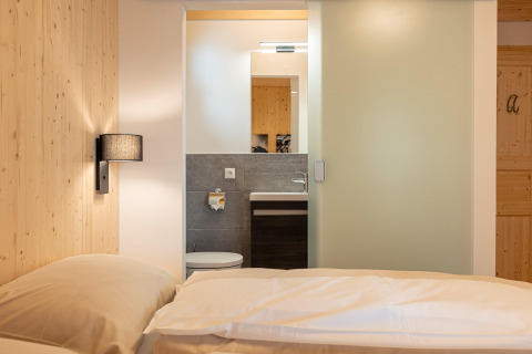 Slaapkamer in Nature Chalets Turracher Höhe 1 boomhut in Oostenrijk met uitzicht op bed en badkamer.