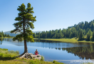 Woman meditating by the lake near the tree houses Nature chalets Turracher Höhe 1 in Austria.