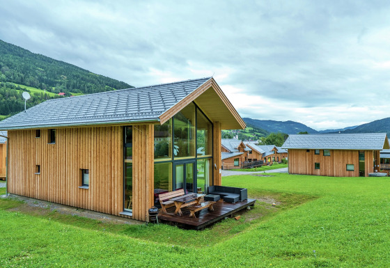 Moderne Kreischberg Chalets 21 aus Holz mit großen Fenstern und Terrasse in grüner alpiner Landschaft.
