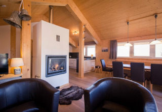 Living room with modern fireplace, leather chairs, and wooden dining area at Alpenpark Turrach 21 in Austria.