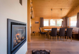Interior view of Alpenpark Turrach 21 chalet in Austria, showing dining area with fireplace.