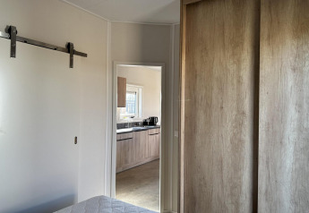 Camera da letto con vista sulla cucina moderna allo Zonneweelde Lodge Deluxe, Camping Zonneweelde, Paesi Bassi.