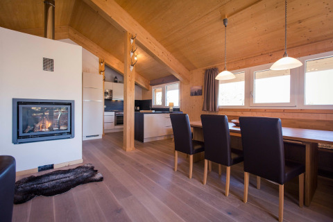Cozy living room at Alpenpark Turrach 21 chalet in Austria featuring a fireplace, dining area, and kitchen.