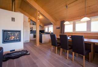 Cozy living room at Alpenpark Turrach 21 chalet in Austria featuring a fireplace, dining area, and kitchen.