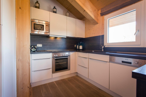 Modern kitchen at chalet Alpenpark Turrach 21 in Austria with white cabinets, wood accents, and appliances.