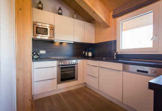 Modern kitchen at chalet Alpenpark Turrach 21 in Austria with white cabinets, wood accents, and appliances.