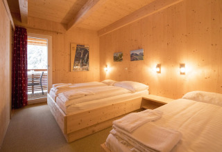 Wooden chalet bedroom at Alpenpark Turrach 21 in Austria, featuring twin beds and a balcony view.