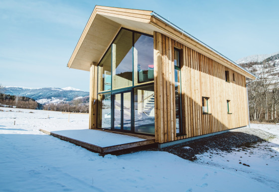 Moderne houten lodge Kreischberg Chalets 27 met grote ramen in een besneeuwd berglandschap.