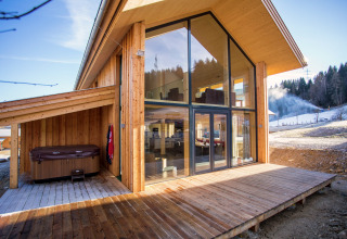 Modernes Holzchalet Kreischberg Chalets 26 in Österreich mit großen Fenstern, Terrasse und Whirlpool.