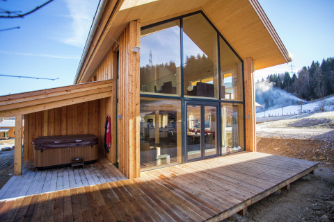 Modernes Holzchalet Kreischberg Chalets 26 in Österreich mit großen Fenstern, Terrasse und Whirlpool.