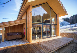 Modernes Holzchalet Kreischberg Chalets 26 in Österreich mit großen Fenstern, Terrasse und Whirlpool.