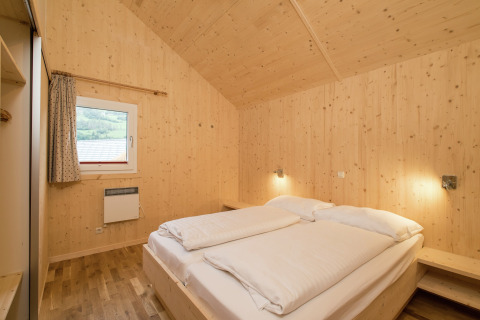 Schlafzimmer aus Holz mit Doppelbett, Nachttischen und Fenster in Kreischberg Chalets 21, Österreich.