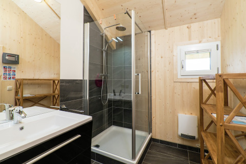 Modernes Bad mit Holzverkleidung, Dusche, Waschbecken und Regal im Kreischberg Chalets 21, Österreich.