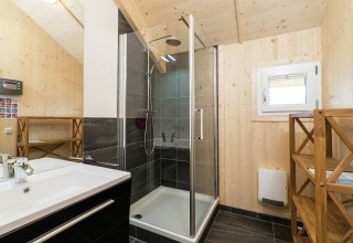 Modernes Bad mit Holzverkleidung, Dusche, Waschbecken und Regal im Kreischberg Chalets 21, Österreich.