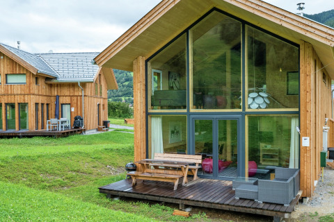 Modernes Holzchalet mit großen Glasfenstern am Kreischberg Chalets 21 in Österreich, umgeben von grüner Natur.