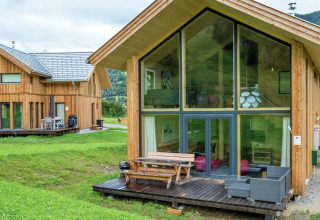 Modernes Holzchalet mit großen Glasfenstern am Kreischberg Chalets 21 in Österreich, umgeben von grüner Natur.