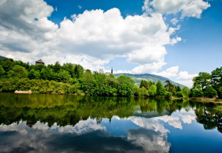 Blick von Kreischberg Chalets 21 in Österreich auf See, grüne Wälder und bewölkten Himmel.