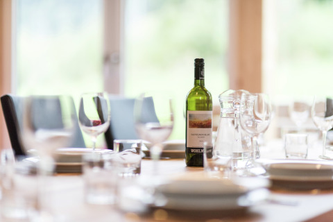 Ein gedeckter Tisch mit Weinflasche und Gläsern im Kreischberg Chalets 21 in Österreich vor dem Essen.