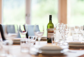 Ein gedeckter Tisch mit Weinflasche und Gläsern im Kreischberg Chalets 21 in Österreich vor dem Essen.