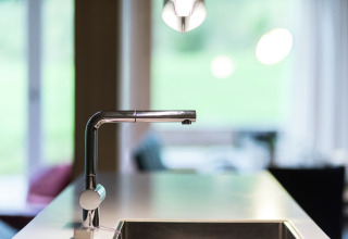 Moderner Küchenwasserhahn im Kreischberg Chalets 21 in Österreich, mit Blick auf ein wohnliches Zimmer.