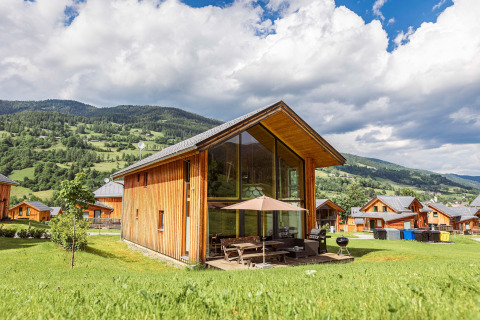 Modernes Holzchalet mit großen Fenstern bei Kreischberg Chalets 21 in Österreich, grüne Berge im Hintergrund.