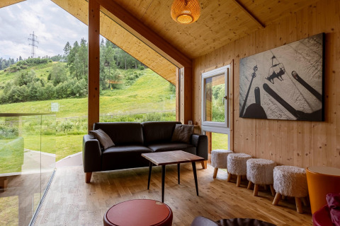 Modernes Wohnzimmer im Kreischberg Chalets 21, Österreich, mit großen Fenstern und Blick ins Grüne.