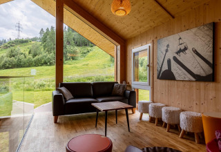 Modernes Wohnzimmer im Kreischberg Chalets 21, Österreich, mit großen Fenstern und Blick ins Grüne.