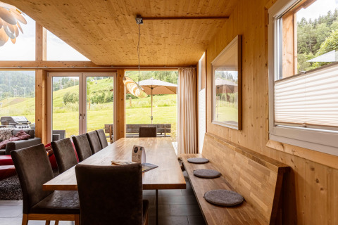 Holzgetäfelter Essbereich im Kreischberg Chalets 21 in Österreich mit Ausblick auf grüne Hügel.