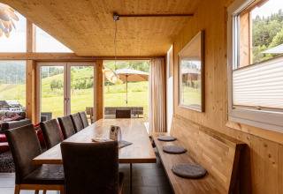 Holzgetäfelter Essbereich im Kreischberg Chalets 21 in Österreich mit Ausblick auf grüne Hügel.