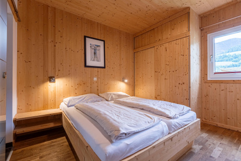 Schlafzimmer mit Holzverkleidung und Doppelbett im Kreischberg Chalets 21, Österreich, hell und gemütlich.