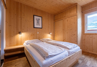 Schlafzimmer mit Holzverkleidung und Doppelbett im Kreischberg Chalets 21, Österreich, hell und gemütlich.