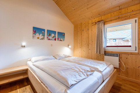 Schlafzimmer im Kreischberg Chalets 21, Österreich, mit Holzverkleidung, Fenster und Doppelbett.