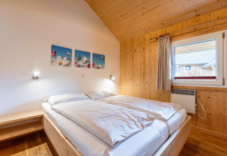 Schlafzimmer im Kreischberg Chalets 21, Österreich, mit Holzverkleidung, Fenster und Doppelbett.
