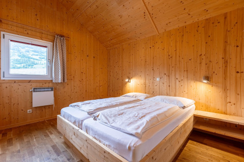 Schlafzimmer mit Holzverkleidung und Doppelbett in Kreischberg Chalets 21, gemütlich in Österreich.