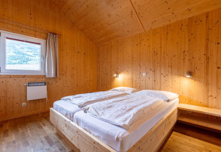 Schlafzimmer mit Holzverkleidung und Doppelbett in Kreischberg Chalets 21, gemütlich in Österreich.