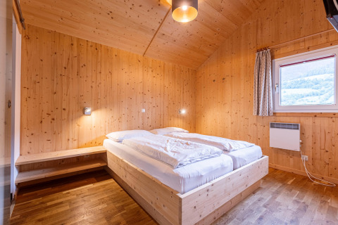 Holzgetäfeltes Schlafzimmer mit Doppelbett und Fenster im Kreischberg Chalets 21 in Österreich.