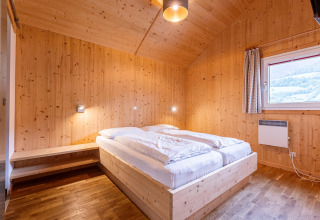 Holzgetäfeltes Schlafzimmer mit Doppelbett und Fenster im Kreischberg Chalets 21 in Österreich.
