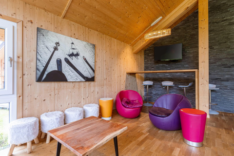 Moderner Wohnraum in Kreischberg Chalets 21, Österreich, mit bunten Stühlen und viel Holzdekor.