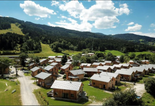 Luftaufnahme von Kreischberg Chalets 21 in Österreich, umgeben von Bergen und grünen Wiesen bei Sonne.