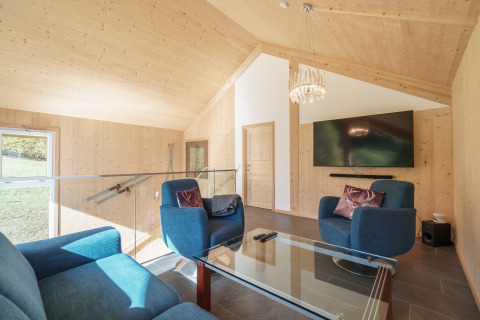 Lichte, moderne woonkamer in Kreischberg Chalets 27 in Oostenrijk met blauwe stoelen en grote tv.