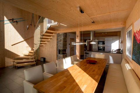 Moderne eetkamer met houten interieur, open keuken en trap in Kreischberg Chalets 27, Oostenrijk.