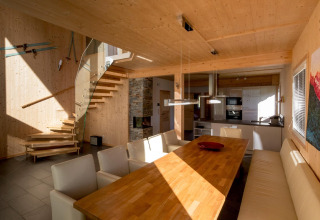 Moderne eetkamer met houten interieur, open keuken en trap in Kreischberg Chalets 27, Oostenrijk.